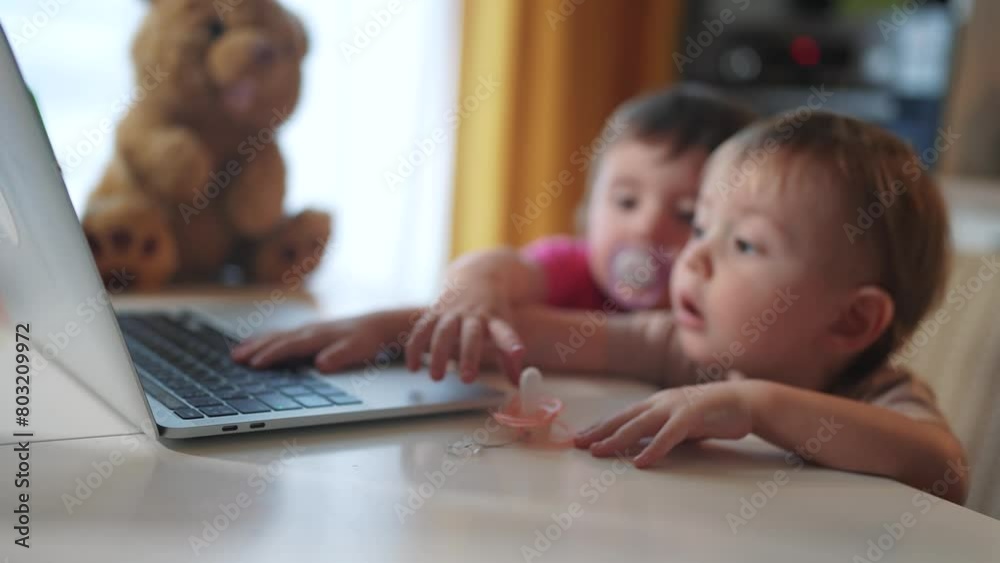 twin baby children a playing laptop watching video in the kitchen. happy family kid dream concept. baby twins playing video game on lifestyle laptop looking at screen in kitchen twin baby children a playing laptop watching video in the kitchen. happy family kid dream concept. baby twins playing video game on lifestyle laptop looking at screen in kitchen