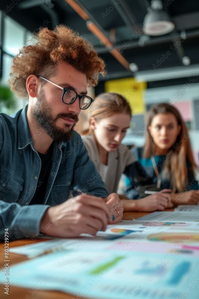 Three people in a meeting looking at graphs and charts Three people in a meeting looking at graphs and charts