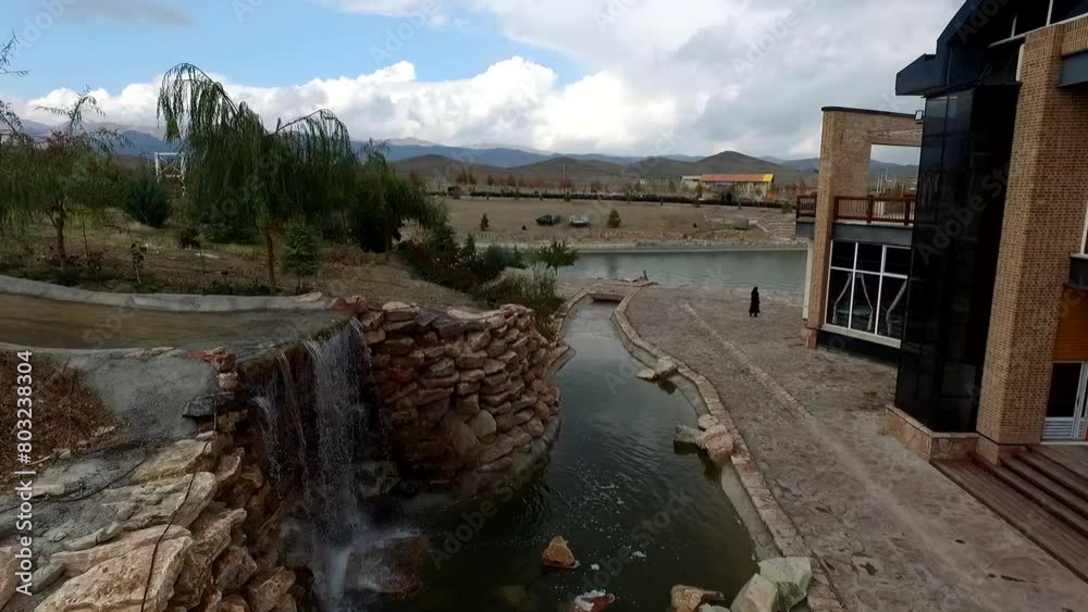 Small artificial waterfall in beautiful lake and modern island. boating people. High resolution and quality aerial footage. Small artificial waterfall in beautiful lake and modern island. boating people. High resolution and quality aerial footage.