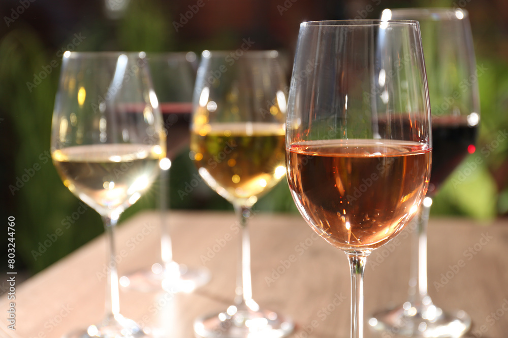 Different tasty wines in glasses against blurred background, closeup