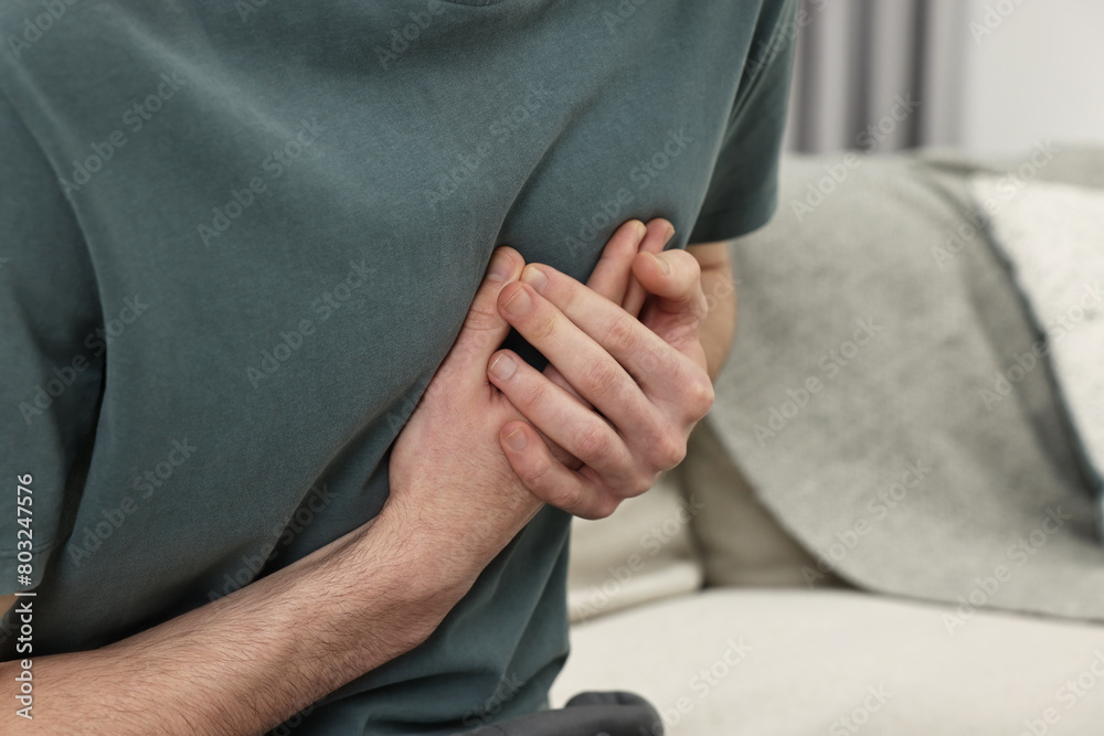 Man suffering from heart hurt on sofa at home, closeup