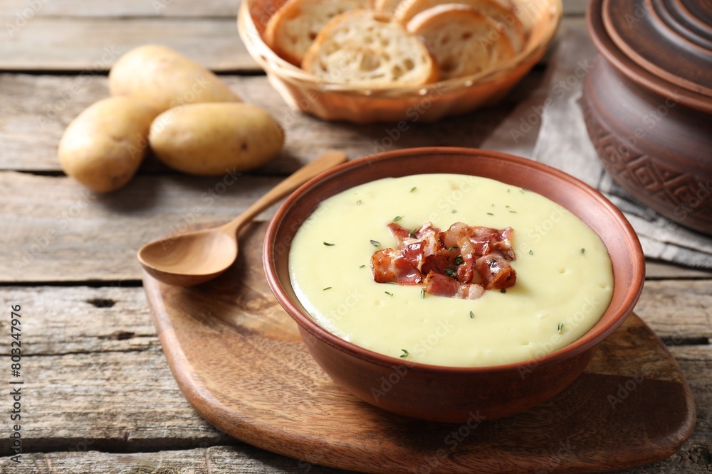 Tasty potato soup with bacon and rosemary in bowl served on wooden table Tasty potato soup with bacon and rosemary in bowl served on wooden table