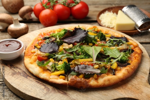Delicious vegetarian pizza and ingredients on wooden table, closeup