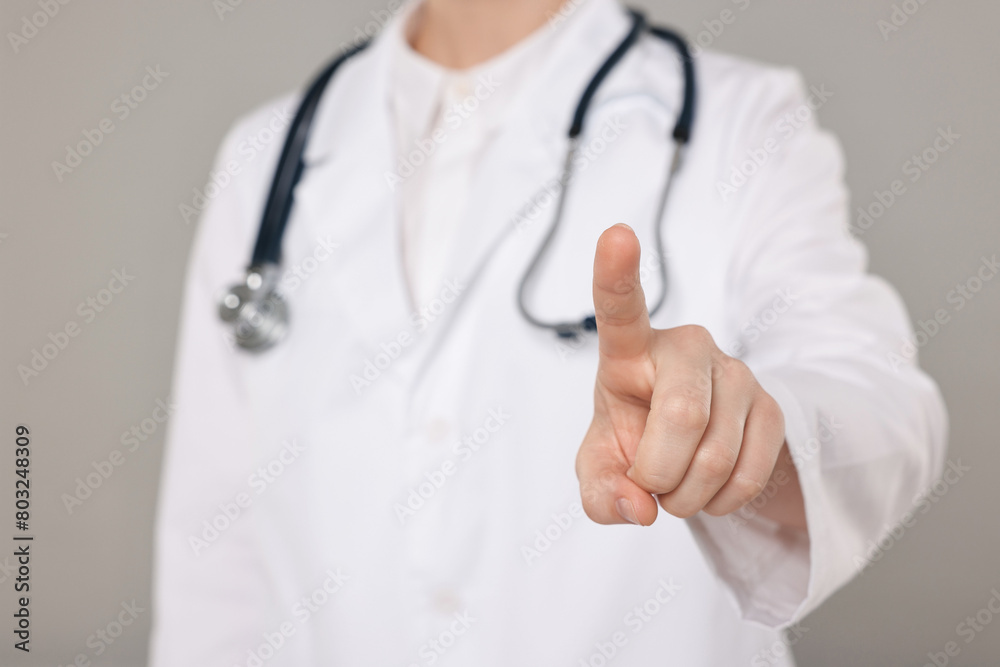 Doctor with stethoscope pointing on grey background, closeup Doctor with stethoscope pointing on grey background, closeup