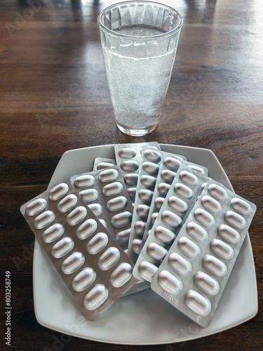Pastiglie e bicchiere di acqua come pranzo di una società malata photo