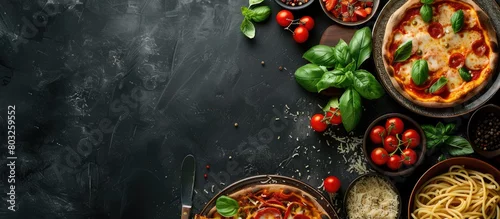 Obraz  z motywem Italian cuisine on a dark backdrop featuring pasta and pizza from a top angle with empty space for text.