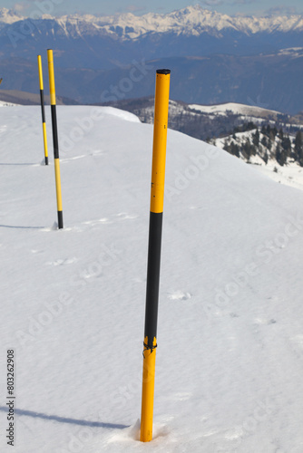 posts stuck in the yellow and black snow to mark the edge of the road after the snowfall in the mountains