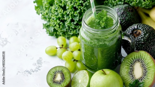 A green smoothie in a mason jar with a white background and green fruits and vegetables.