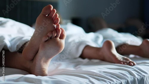 The view of a child's legs sticking out from under a blanket lying on a large snow-white bed illustrates the concept of sleep and peace.