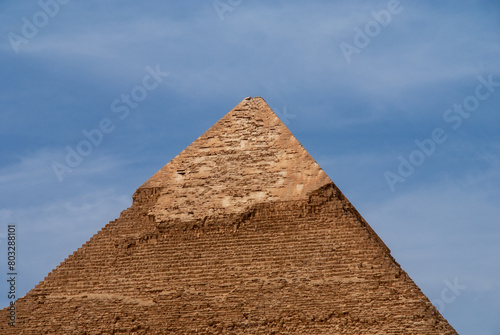Giza Pyramid Complex is complex of ancient monuments on Giza Plateau in suburbs of Cairo. Pyramid of Khafre Khafre) against background of blue spring sky.