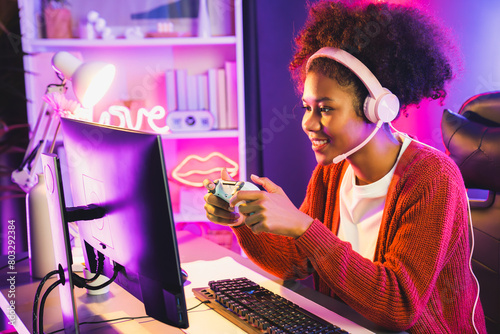 African American girl streamer playing online fighting with Esport skilled team wearing headphones in neon color lighting room. Talking other players planing strategies to win competitors. Tastemaker.