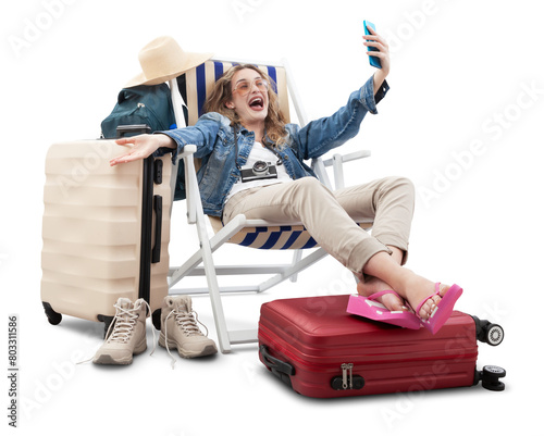 Happy joyful tourist woman in travel attire, on deck chair with trolley suitcases, make selfie with mobile phone. Summer beach holiday, flight and vacation travel booking. Travel influencer lifestyle