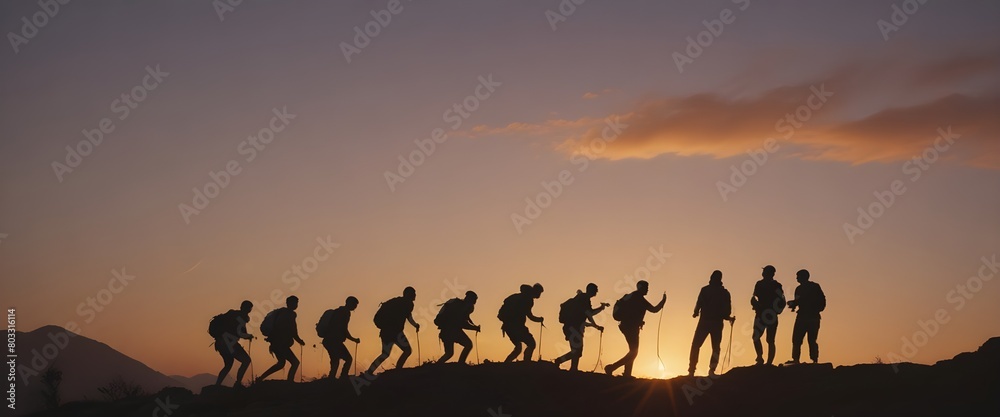 A group of people silhouetted against a sunset, helping each other climb up a rocky mountain path. Help and assistance concept.