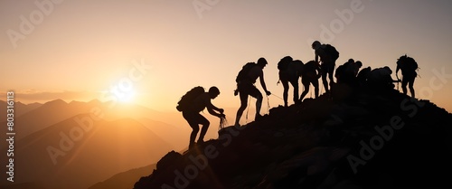 A group of people silhouetted against a sunset, helping each other climb up a rocky mountain path. Help and assistance concept. photo