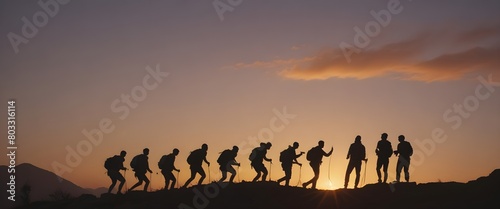 A group of people silhouetted against a sunset, helping each other climb up a rocky mountain path. Help and assistance concept.