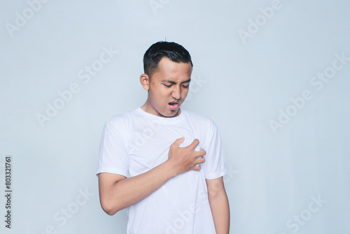 Asian young man in white t-shirt holding his heart on the left chest.