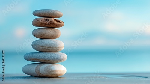 A perfectly balanced stack of smooth  river-worn pebbles  set against a serene  sky-blue studio background.