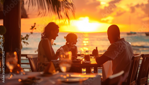 Fototapeta Naklejka Na Ścianę i Meble -  Close-up of family on holiday or vacation eating near a beach a la carte with the blue sea in the background