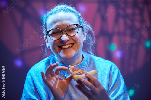 Adult happy woman in glasses eating pizza