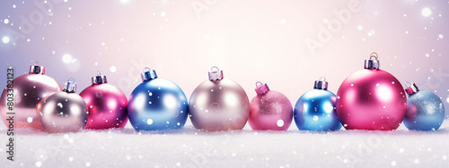 Collection of pastel-colored Christmas balls lined up against a snowy, sparkling backdrop. photo