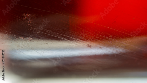 Scratches and dirt on transparent glass on blurred red and dark.