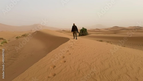 Man walking through the dunes of Merzouga in Morocco photo