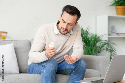 Ill young man holding pills...