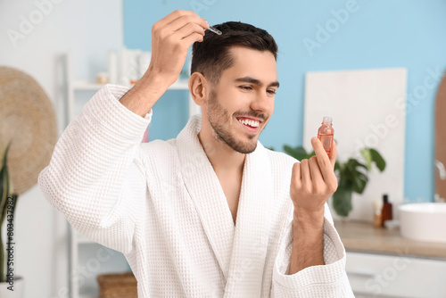 Young man applying serum fo...