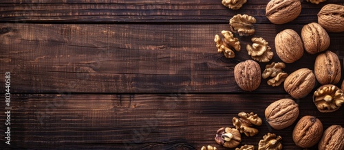 Close-up image of whole walnuts and their kernels on a dark wooden table with empty space for text placement