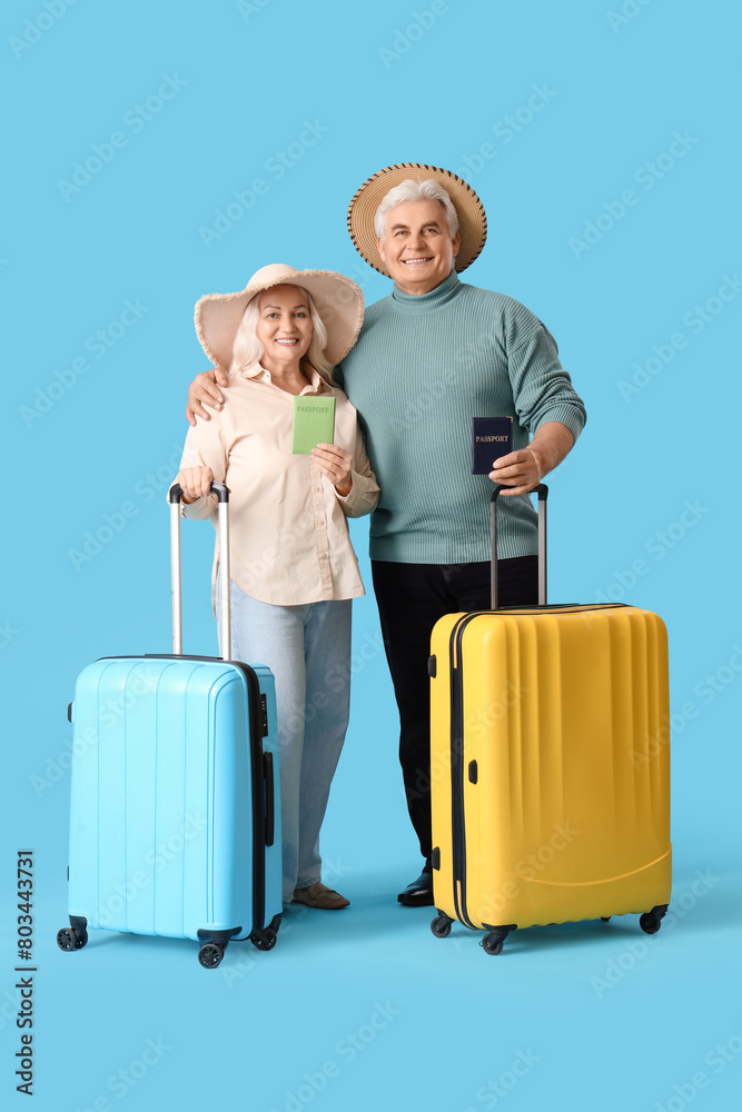 Mature couple with passports and suitcases ready for summer vacation on blue background Mature couple with passports and suitcases ready for summer vacation on blue background