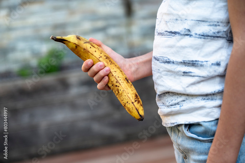 Profile closeup view of a child holding a very ripe banana