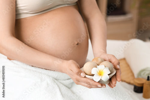 Young pregnant woman with flower and massage balls in spa salon, closeup © Pixel-Shot