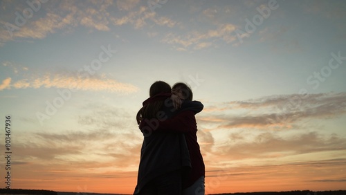 Girls friends hugging at sunset in park, silhouettes. Happy smiling girls women acquaintance friends girlfriends hugging embracing cuddling at sunset dawn sky clouds. Nice meeting, close relationship