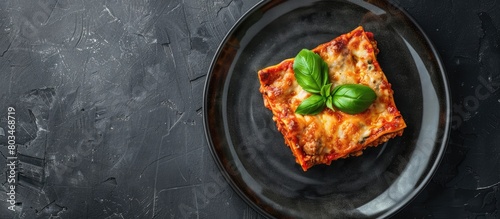Lasagna with a basil leaf on a gray plate, showcasing Italian cuisine and a homemade meat lasagna, with space for text, seen from above.