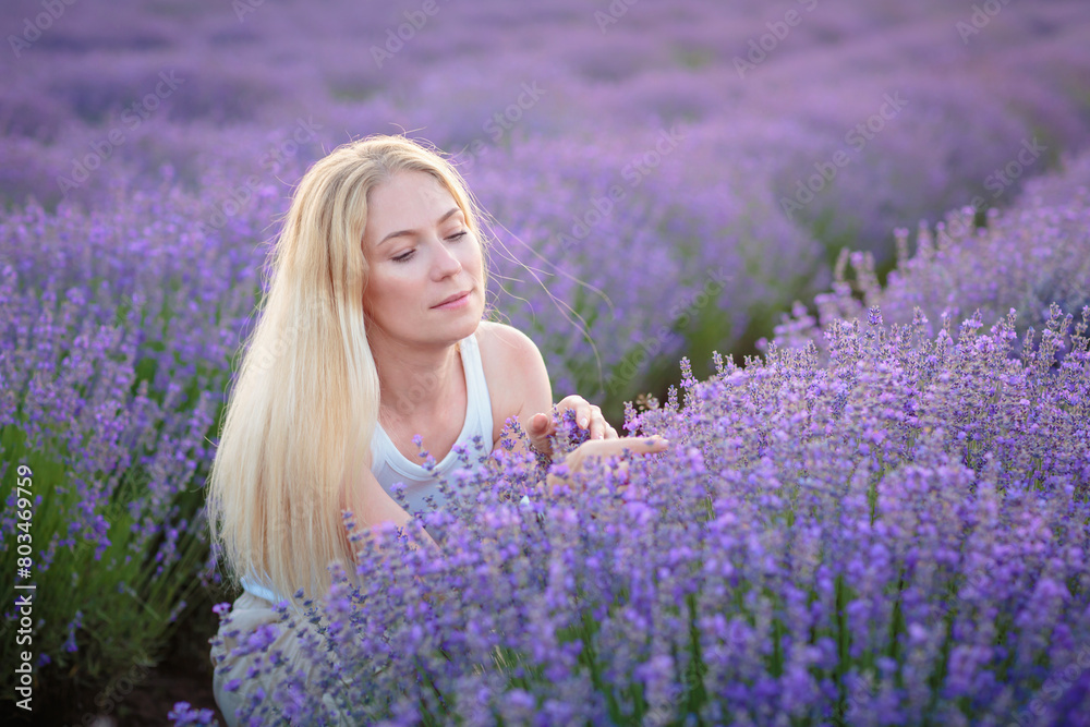 Lavender field. Young attractive woman with blond hair walking between rows of lavender flowers, posing for camera, relaxing, resting, enjoying nature, smelling and touching flowers. Mental health Lavender field. Young attractive woman with blond hair walking between rows of lavender flowers, posing for camera, relaxing, resting, enjoying nature, smelling and touching flowers. Mental health