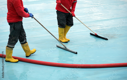 Workers cleaning floors with squeegees photo