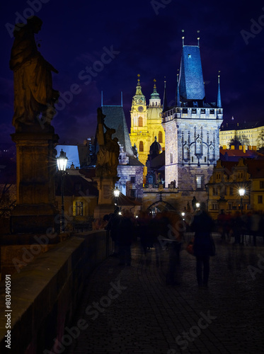 Prague, Czech Republic. Night time at Charles Bridge. Pedestrian way with statues and paving stones. Vew the old tower. Antique medieval Tower arch. Town Mala Strana district of prague photo