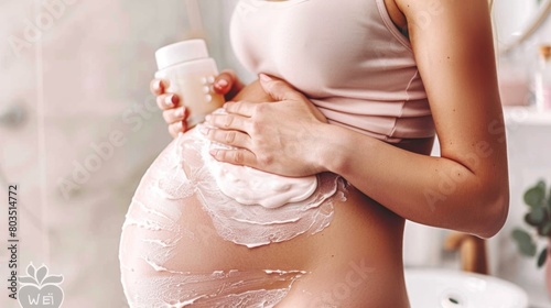 A close-up of a Caucasian woman hands applying stretch mark cream to her belly, in a softly lit, neutral-toned bathroom photo