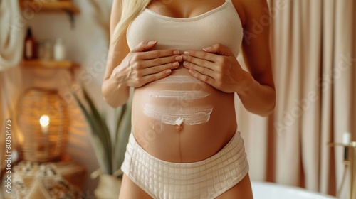 A close-up of a Caucasian woman hands applying stretch mark cream to her belly, in a softly lit, neutral-toned bathroom photo