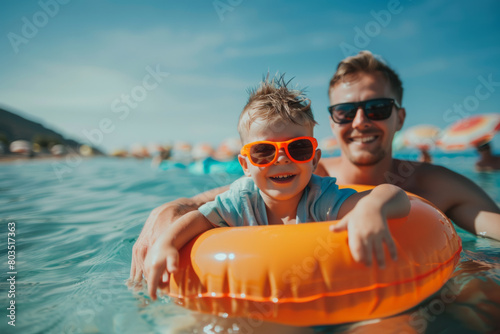 Father and son in sunglasses with inflatable ring at beach, having fun on summer vacation