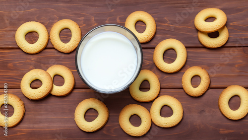 Ring-shaped cookies and a glass of milk on a wooden background