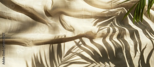 Palm leaf shadows cast on a beige linen fabric background, creating a summer vacation and beach holiday ambiance.