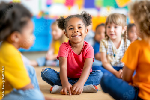 Group of small nursery school children sitting and listening to teacher on floor indoors in classroom