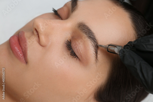 Foto Beautician making permanent eyebrow makeup to young woman, closeup