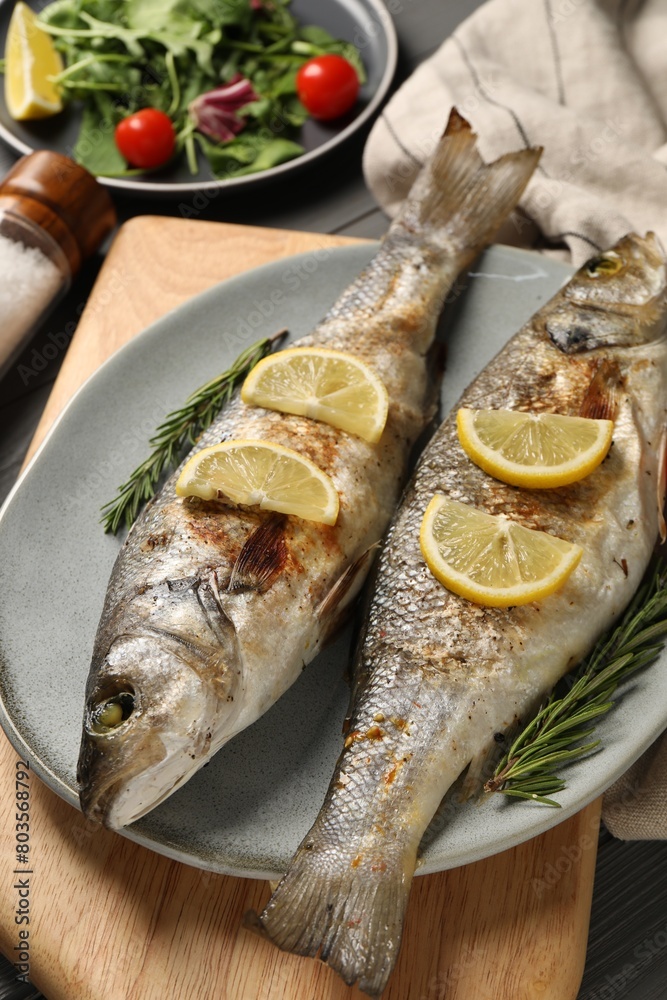 Delicious baked fish, lemon and rosemary on table Delicious baked fish, lemon and rosemary on table
