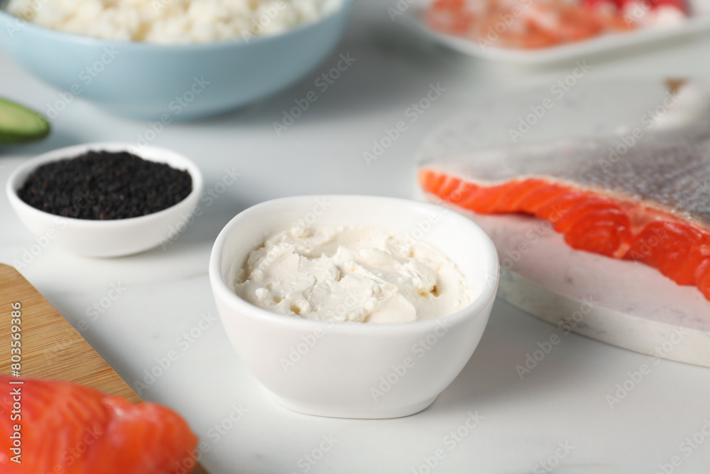Cream cheese in bowl and other ingredients for sushi on white table, closeup Cream cheese in bowl and other ingredients for sushi on white table, closeup