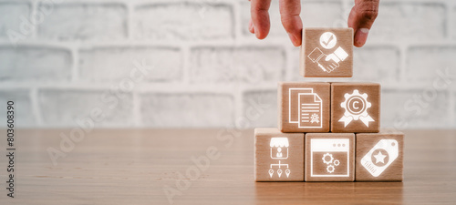 Intangible assets concept, Hand holding wooden block on desk with intangible assets icon on virtual screen.