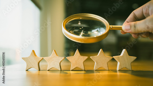 A magnifying glass and 5 stars arranged on a table, a review, rating and survey concepts.