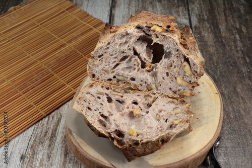 Cutting traditional walnut sour dough on the wooden board. Famous bread bakery in French. 