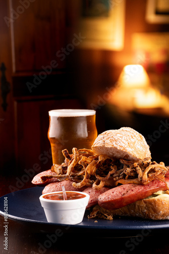 bock sausage sandwich with baguette crispy onion and pepper sauce paired with craft beer ale ipa apa and blurred pub background